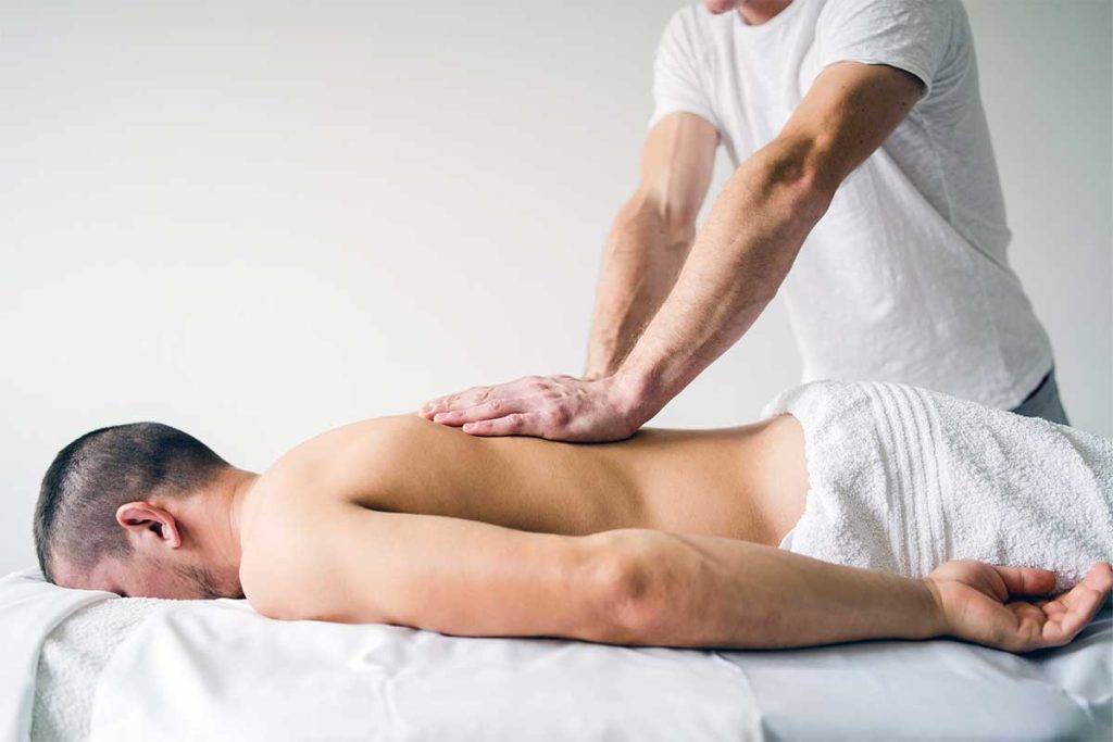 Client lying face down on a massage table receiving a back massage from a mobile massage therapist in Bristol